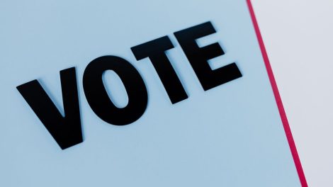 Close-up da palavra “VOTE” em composição minimalista sobre fundo claro.