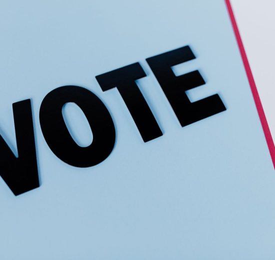 Close-up da palavra “VOTE” em composição minimalista sobre fundo claro.