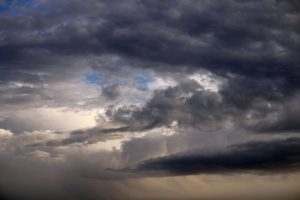 Nuvens cumulonimbus densas e escuras formam um céu carregado, indicando a aproximação de uma tempestade.