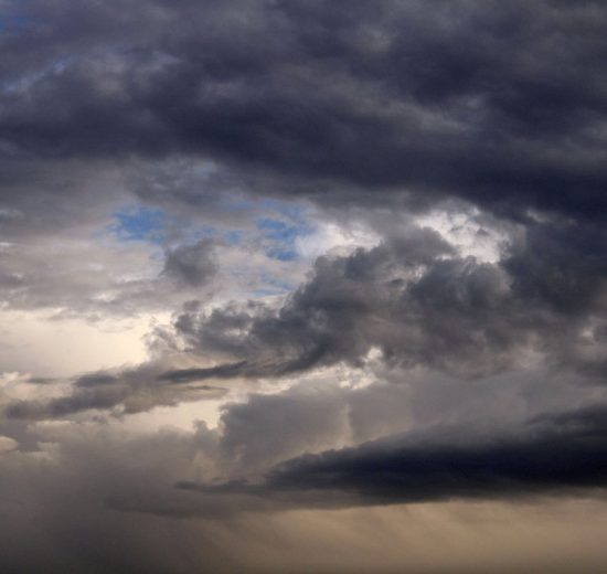 Nuvens cumulonimbus densas e escuras formam um céu carregado, indicando a aproximação de uma tempestade.