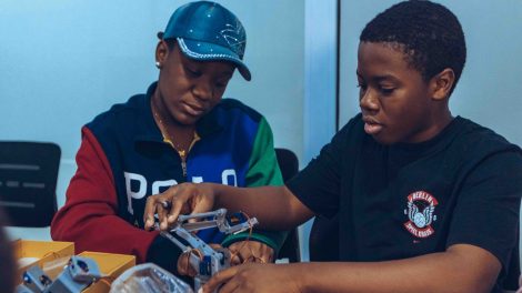 Dois estudantes montam um robô durante uma atividade prática de tecnologia.